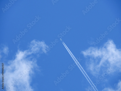 青空を上昇する白い飛行機と飛行機雲