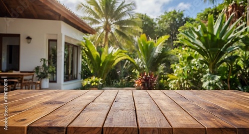 Empty wood table top on a tropical home terrace setting with a blurred background. The focus is on the table surface.