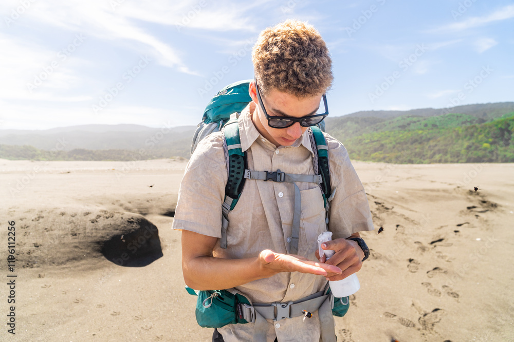 A young mountaineer preparing for the hike by applying sunscreen, ensuring protection from the sun during the outdoor adventure.