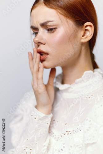 A thoughtful young woman with red hair in a white blouse expressing concern, showcasing emotions related to personal reflection and self awareness