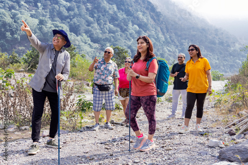 Senior friends admiring beauty of nature while hiking together in forest on sunny day during adventure weekend