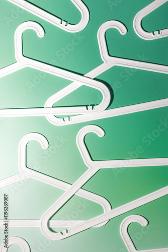 White Clothes hangers as creative minimal composition on pastel green gradient background, Plastic rack creating modern and geometric aesthetic, top view, flat lay creative photo pattern photo