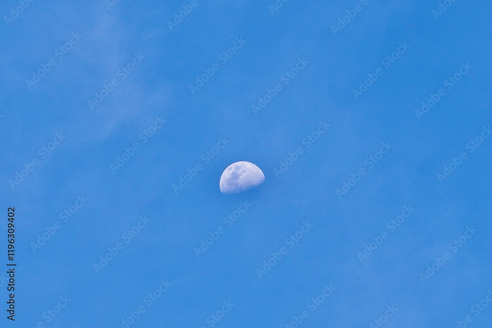 Beautiful half white moon visible on sunny daytime blue sky isolated on horizontal outdoor environment background. Beautiful half white moon visible on sunny daytime blue sky isolated on horizontal outdoor environment background.