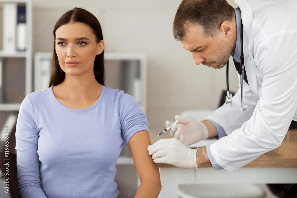 Obraz premium Immunization. Adult male doctor giving intramuscular injection to a woman. Physician injecting vaccine to patient at hospital or clinic office. Medicine cure and treatment concept
