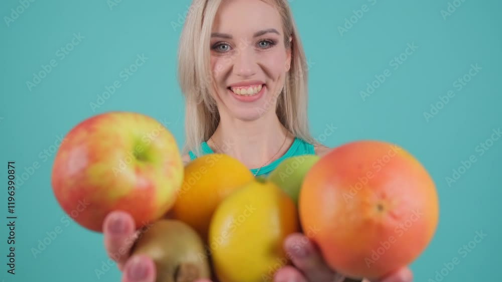 A young woman highlights a colorful combination of fresh fruits such as apples and berries, demonstrating the process of losing weight A young woman highlights a colorful combination of fresh fruits such as apples and berries, demonstrating the process of losing weight