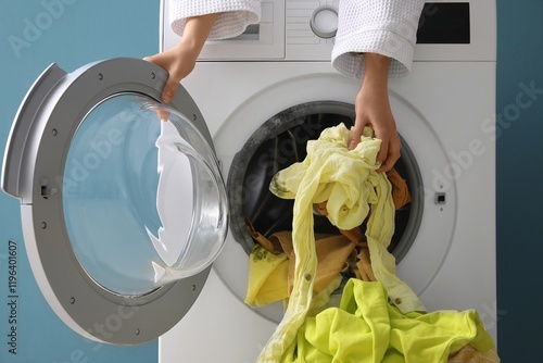 Woman putting dirty clothes in washing machine with black mold at home photo