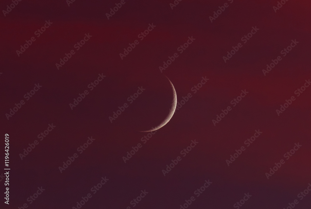 A crescent moon is in the sky above a red background A crescent moon is in the sky above a red background