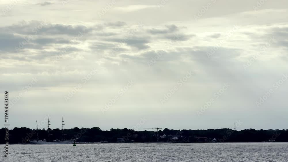 Quiet Moment on the North Sea Lone Sailboat Drifts Along the Coast, Silhouetted Against the Dramatic Sky as Storm Clouds Gather on the Horizon Quiet Moment on the North Sea Lone Sailboat Drifts Along the Coast, Silhouetted Against the Dramatic Sky as Storm Clouds Gather on the Horizon