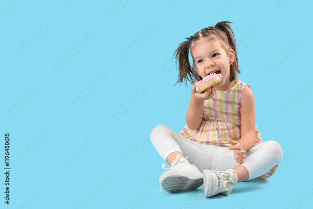 Cute little girl sitting on floor with tasty donut on blue background Cute little girl sitting on floor with tasty donut on blue background