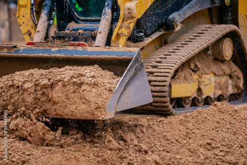 Track compact loader working in construction project leveling the ground and excavating materials for preparation of building project photo