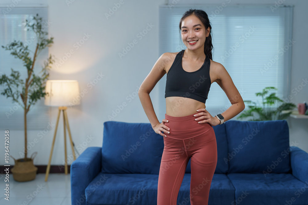 Confident and healthy young asian woman smiling while posing in sportswear in her modern living room, showcasing a fit and active lifestyle Confident and healthy young asian woman smiling while posing in sportswear in her modern living room, showcasing a fit and active lifestyle