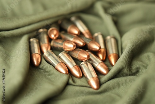 Many 9mm pistol bullets stacked on green camo military uniform fabric photo