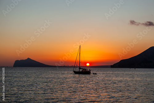 Fototapeta Naklejka Na Ścianę i Meble -  Sailboat view at sunset over Benidorm town in the province of Alicante, Valencian Community, Spain. Costa Blanca Mediterranean sea coast.