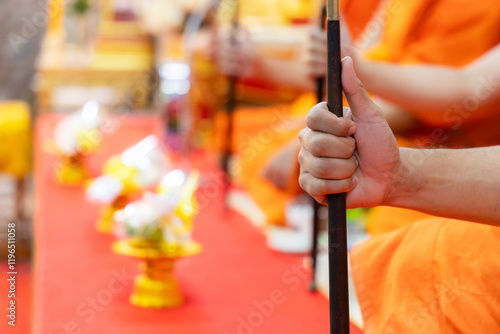 A close-up of a monk’s hands holding a traditional talapat (Buddhist prayer beads) during a sacred Buddhist ceremony. This serene and symbolic image captures the essence of devotion in Thai Buddhism. photo