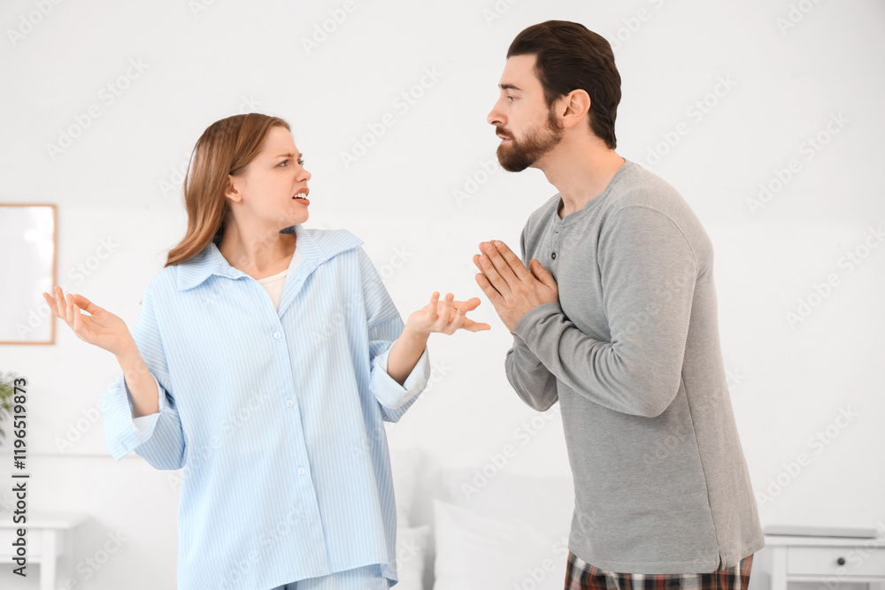 Fototapeta premium Young man apologizing to his angry wife in bedroom