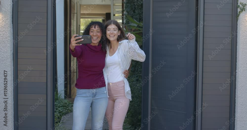 Taking selfie, lesbian couple smiling and standing together outside home Taking selfie, lesbian couple smiling and standing together outside home