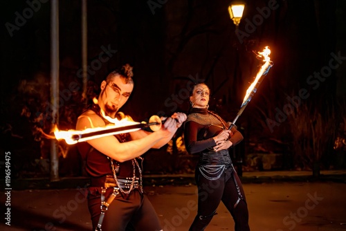 Two fire dancers performing with burning swords in a night show, creating a mesmerizing spectacle photo