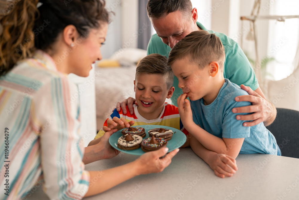 Caucasian family shares homemade chocolate cupcakes in bright kitchen setting, parents and children gathered around white table wearing casual attire. Caucasian family shares homemade chocolate cupcakes in bright kitchen setting, parents and children gathered around white table wearing casual attire.