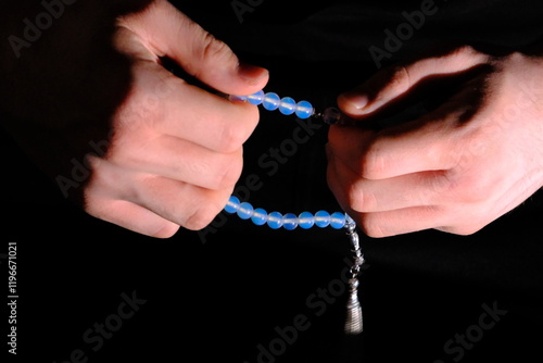 Close-up hands holding rosary beads on a black background. Ramadan, Islamic holy days, Miraj Kandili, Eid al-Fitr, Eid al-Adha. To pray, to worship. Blessed days. photo