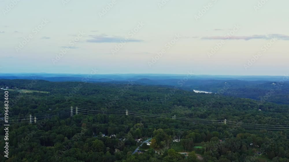 Drone fly-in capturing the expansive forests, rolling hills, and residential pockets of Yorktown Heights, NY. Scenic view with serene pastel skies at dusk.