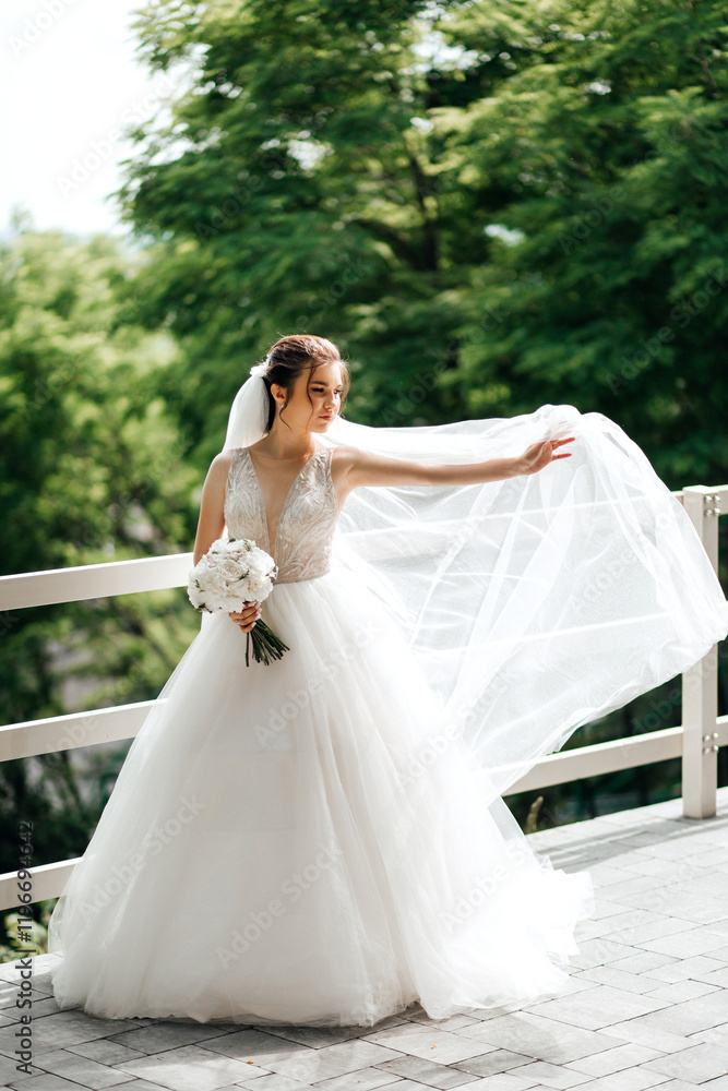 bride in a wedding dress. She is standing on the street against a background of green trees. The dress is white with a full skirt and a deep V-neck top. bride in a wedding dress. She is standing on the street against a background of green trees. The dress is white with a full skirt and a deep V-neck top.