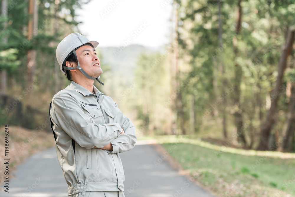 Naklejka premium 公園・森林で樹木をチェックする作業着姿の林業の男性 