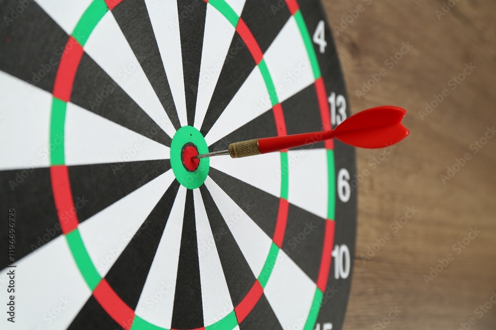 Dart board and red arrow on wooden background, closeup Dart board and red arrow on wooden background, closeup