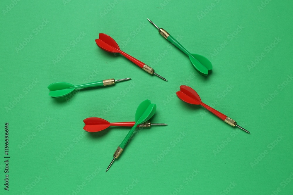 Colorful dart arrows on green background, flat lay Colorful dart arrows on green background, flat lay