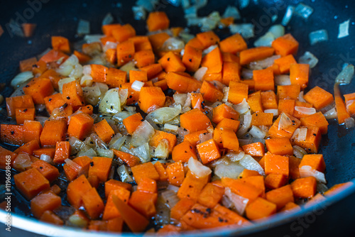 Diced carrots and onions are fried in a pan. Background with the texture of roasted vegetables. photo