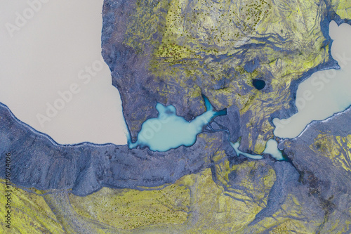 Aerial view of turquoise ponds in a mossy canyon, South Iceland's rugged terrain.