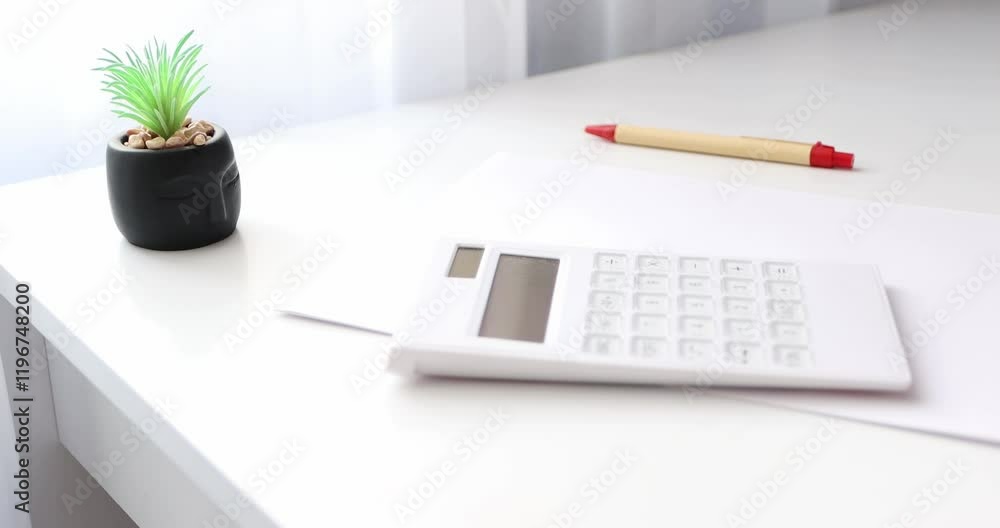 The female hand of a businessman puts a paper, calculator and pen on her table. Close-up on a white background. The female hand of a businessman puts a paper, calculator and pen on her table. Close-up on a white background.