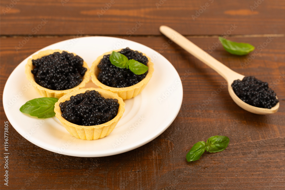 Tartlets with black caviar served on on wooden table Tartlets with black caviar served on on wooden table