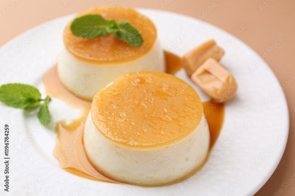 Tasty puddings with caramel sauce served on light brown background, closeup Tasty puddings with caramel sauce served on light brown background, closeup