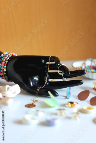 Obraz na płótnie Hand figurine, sunglasses, gold jewelry, colorful bead jewelry, statement rings and various hair accessories on the white table. Selective focus. w salonie