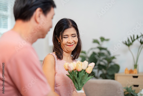 Senior couple celebrating Valentine's Day with a bouquet of flowers at home photo