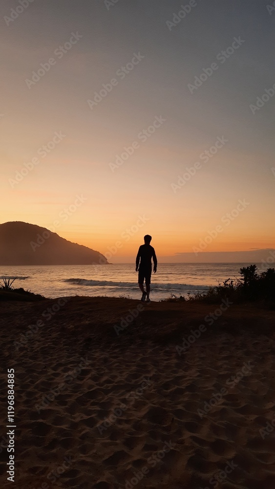 silhueta de homem caminhando na praia no nascer do sol, em ubatuba, são paulo silhueta de homem caminhando na praia no nascer do sol, em ubatuba, são paulo