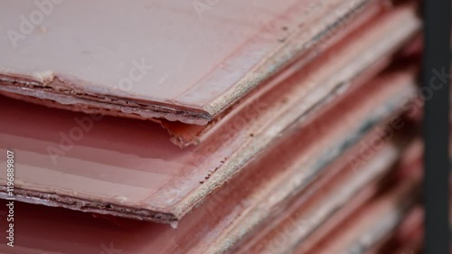 A panning close-up shot of sheets of copper cathodes stacked on top of each other.