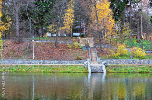 Obraz na płótnie Autumn reflections by the serene lake surrounded by colorful foliage and stone steps w salonie