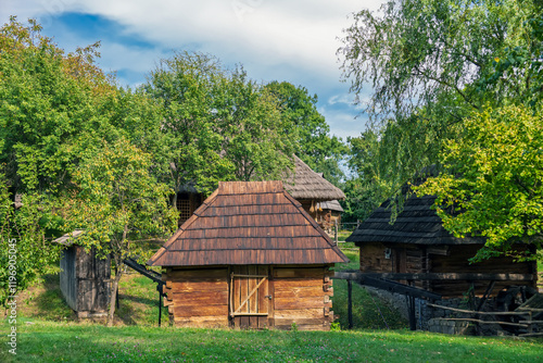 Wooden old village house on a picturesque green meadow. Traditional quiet forest clearing with a rustic old cabin and serene surroundings