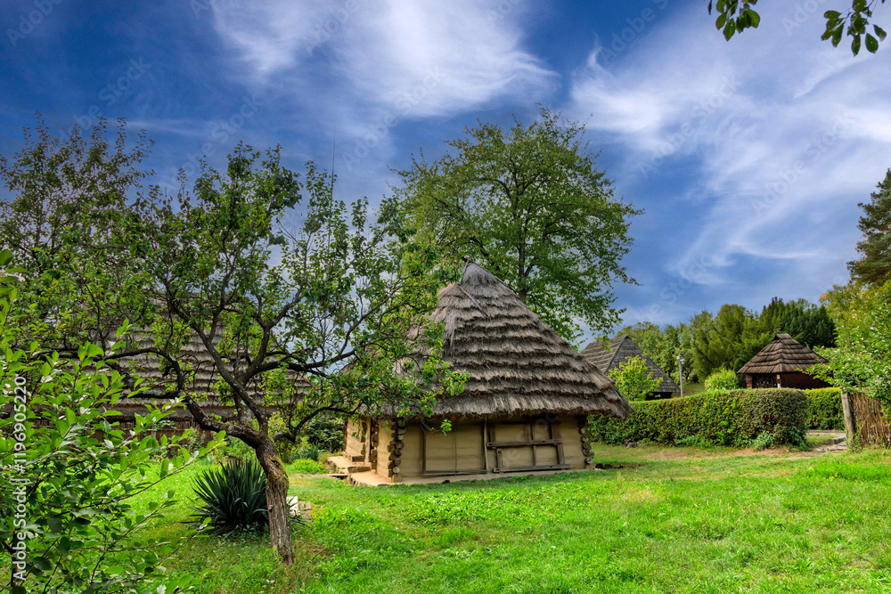 Historic wooden homestead with traditional roof in summer landscape. Ancient rural log building. Rustic wooden house with shingle roof in countryside museum Historic wooden homestead with traditional roof in summer landscape. Ancient rural log building. Rustic wooden house with shingle roof in countryside museum