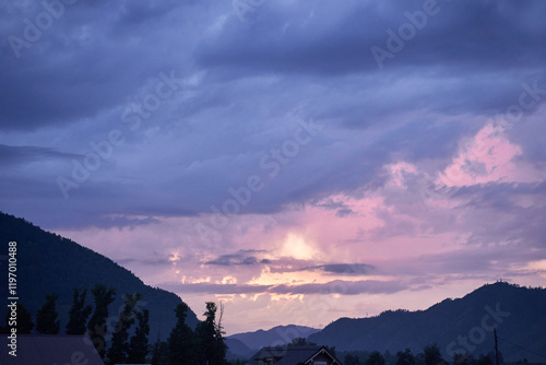 Peaceful evening sky with purple clouds and mountain silhouettes at sunset. photo