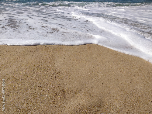 Serene beach scene: foamy waves gently lapping golden sand. Perfect for travel, nature, or summer themes photo