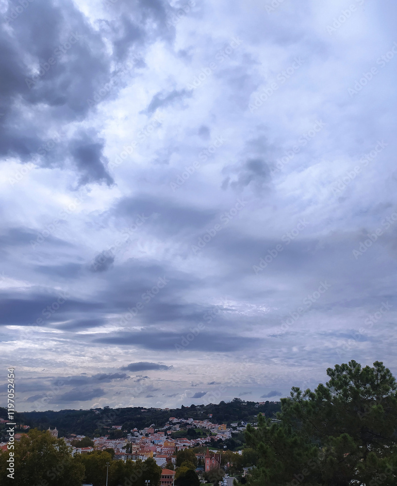 Dramatic cloud formations over a hillside town in the late afternoon sunlight highlighting the landscape's beauty Dramatic cloud formations over a hillside town in the late afternoon sunlight highlighting the landscape's beauty