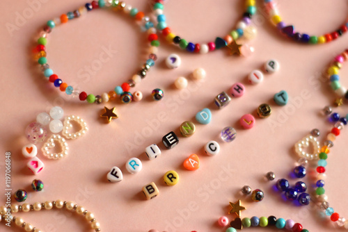 Obraz na płótnie Friendship bracelet spelled with letter beads. Colorful handmade bracelets and various beads. Selective focus, pink background. w salonie