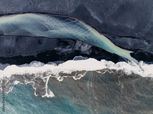 Aerial view of a glacial river merging with the ocean on a black sand beach in South Iceland... photo