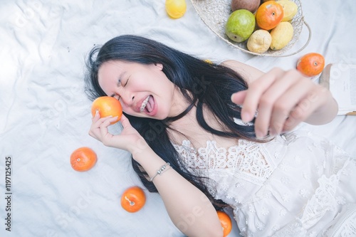 Young Woman Enjoying Fresh Citrus Fruits on Soft White Bedding