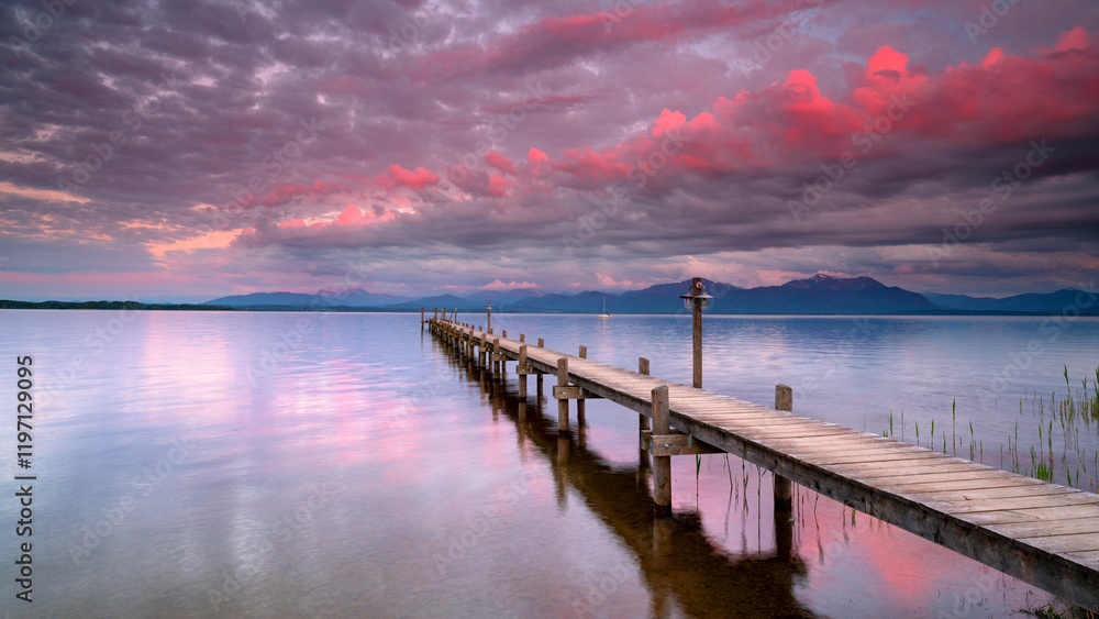 pink clouds in the sunrise light over calm lake with vintage wooden footbridge pink clouds in the sunrise light over calm lake with vintage wooden footbridge