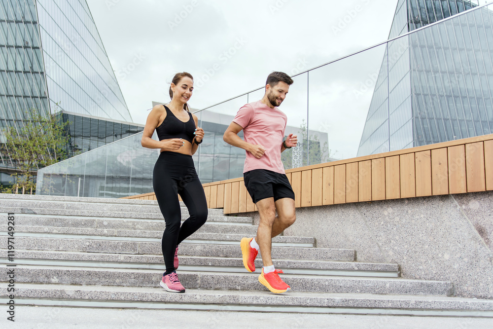 Fototapeta premium Couple enjoys a morning run down the stairs in an urban park with modern architecture
