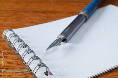 A fountain pen with a pen and a notebook on a wooden table