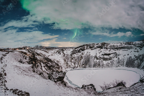 Northern lights above the snow-covered Kerid Crater and frozen lake in south Iceland